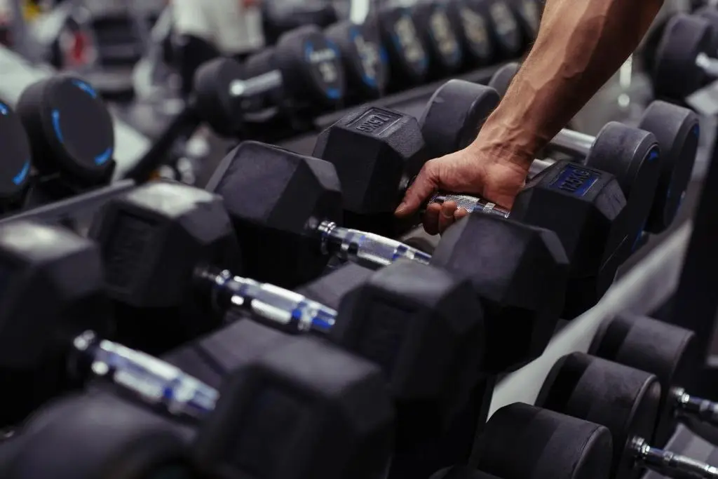 a person is picking up a bunch of black dumbbells at The Aberdeen Dyce Hotel in Dyce