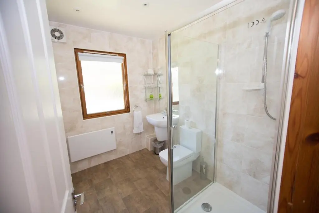 a bathroom with a toilet and a glass shower at Invercauld Lodges in Ballater