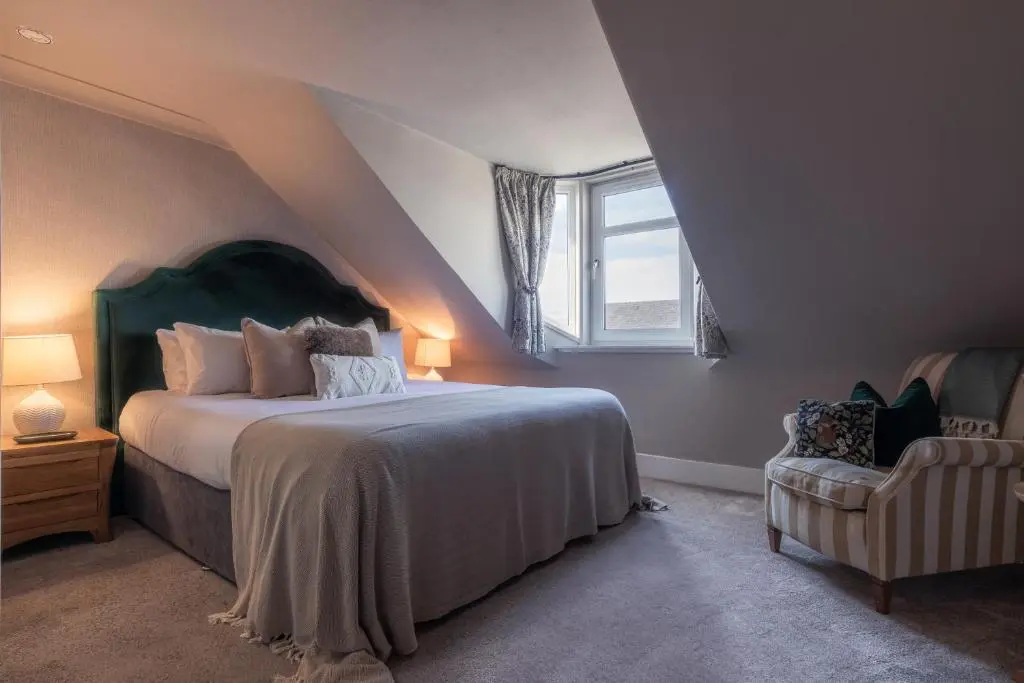 a bedroom with a bed and a window and a chair at The Nessting Place in Inverness