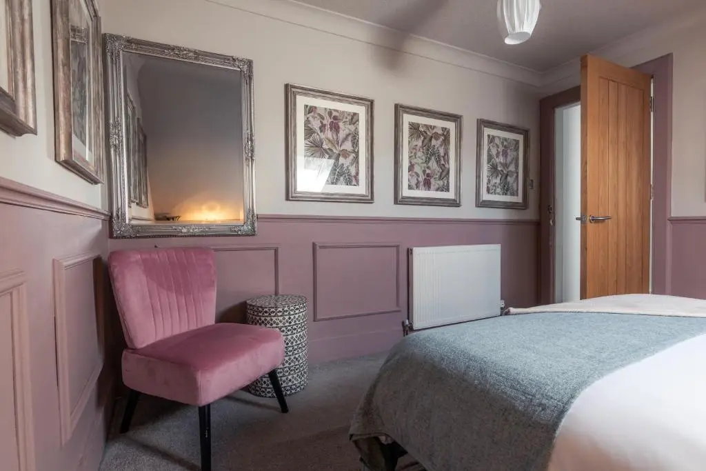 a bedroom with a bed and a chair and a mirror at The Nessting Place in Inverness