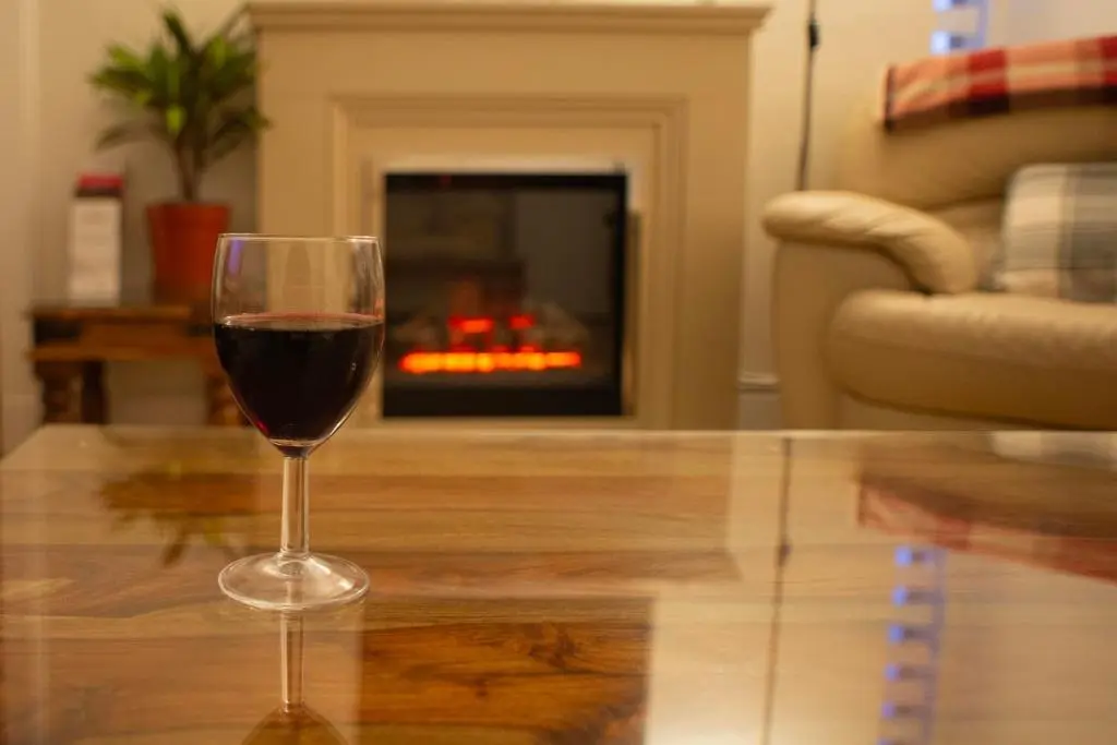 a glass of wine sitting on a table in front of a fireplace at Dunvegan Bed & Breakfast in Dufftown