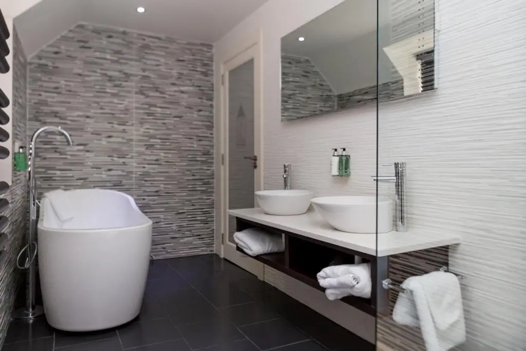a bathroom with two sinks and a large tub at The Dowans Hotel of Speyside in Aberlour