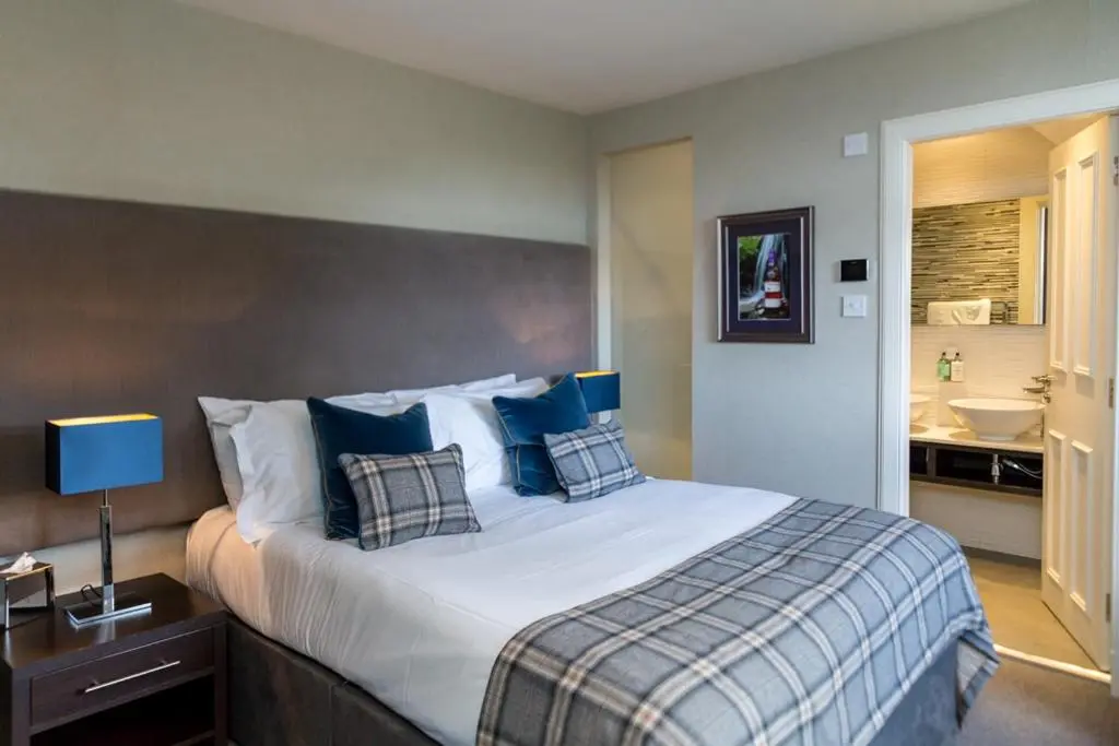 a bedroom with a large bed with blue pillows at The Dowans Hotel of Speyside in Aberlour