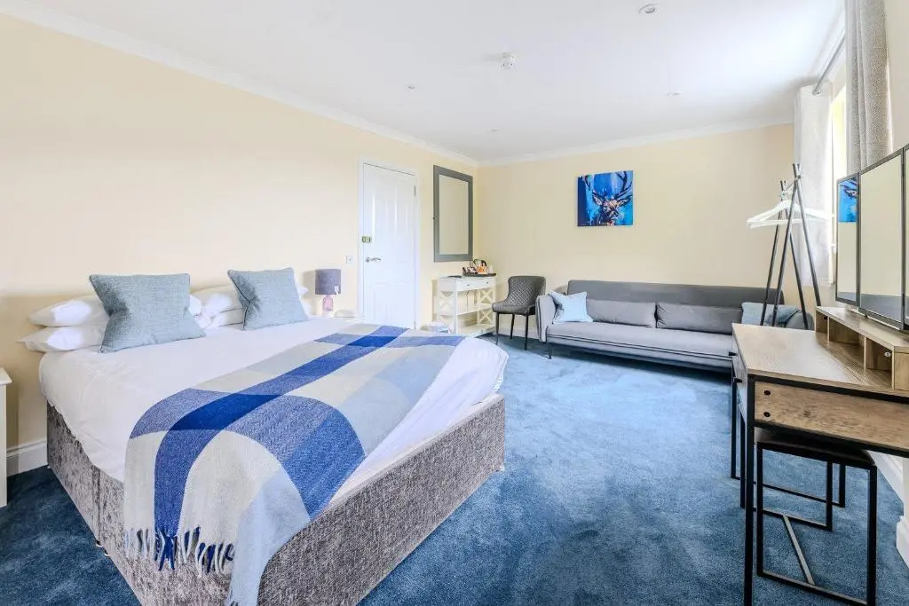a bedroom with a bed and a living room at Loch Ness Clansman Hotel in Drumnadrochit