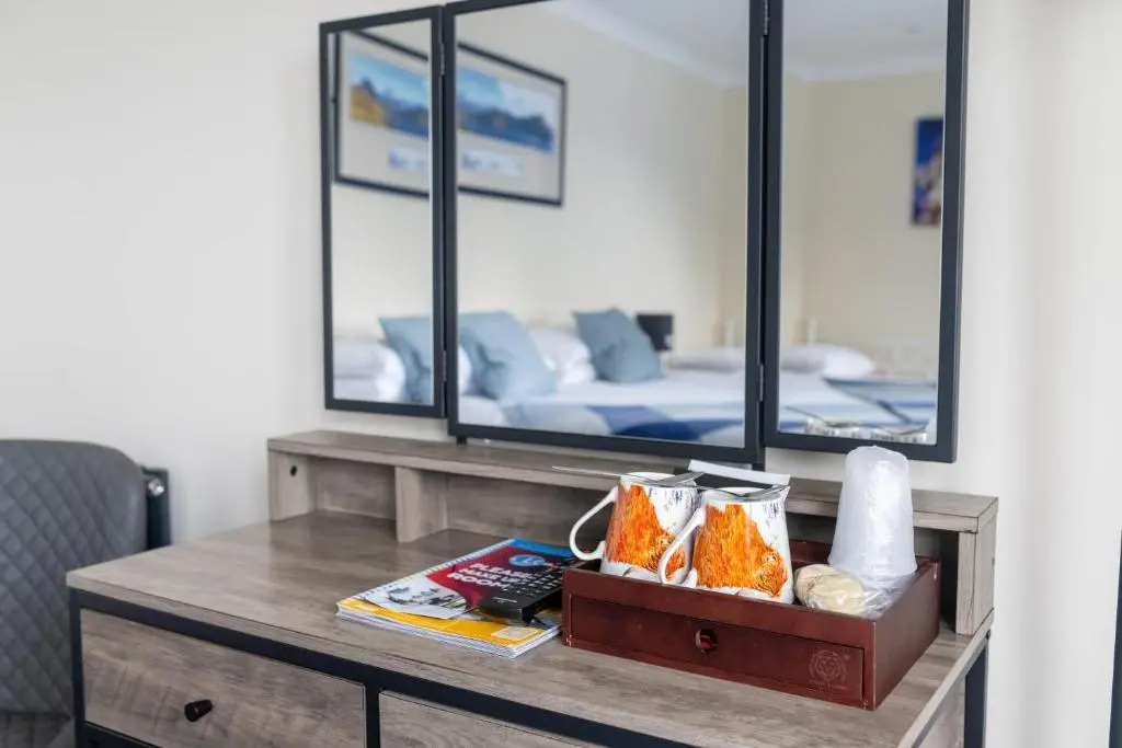 a desk with a mirror and a bed in a room at Loch Ness Clansman Hotel in Drumnadrochit