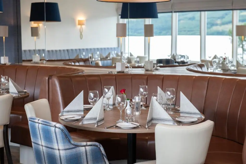 a dining room with a table and chairs with glasses at Loch Ness Clansman Hotel in Drumnadrochit