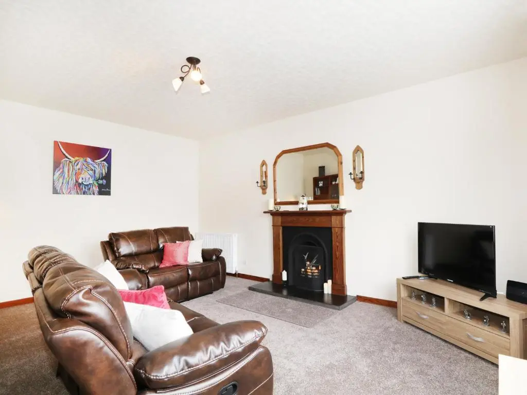 a living room with a couch and a television at Dalnahaven in Grantown on Spey
