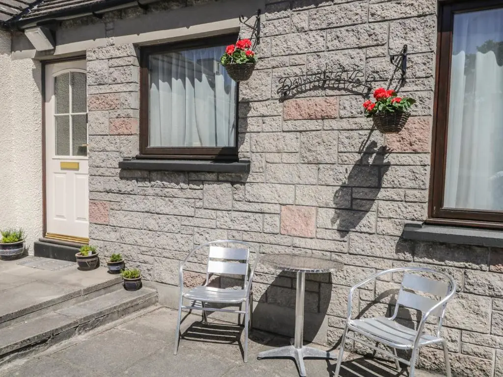 two chairs and a table in front of a building at Dalnahaven in Grantown on Spey