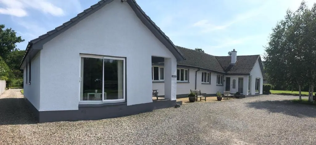 a white house with a large window on a driveway at Aslaich in Drumnadrochit