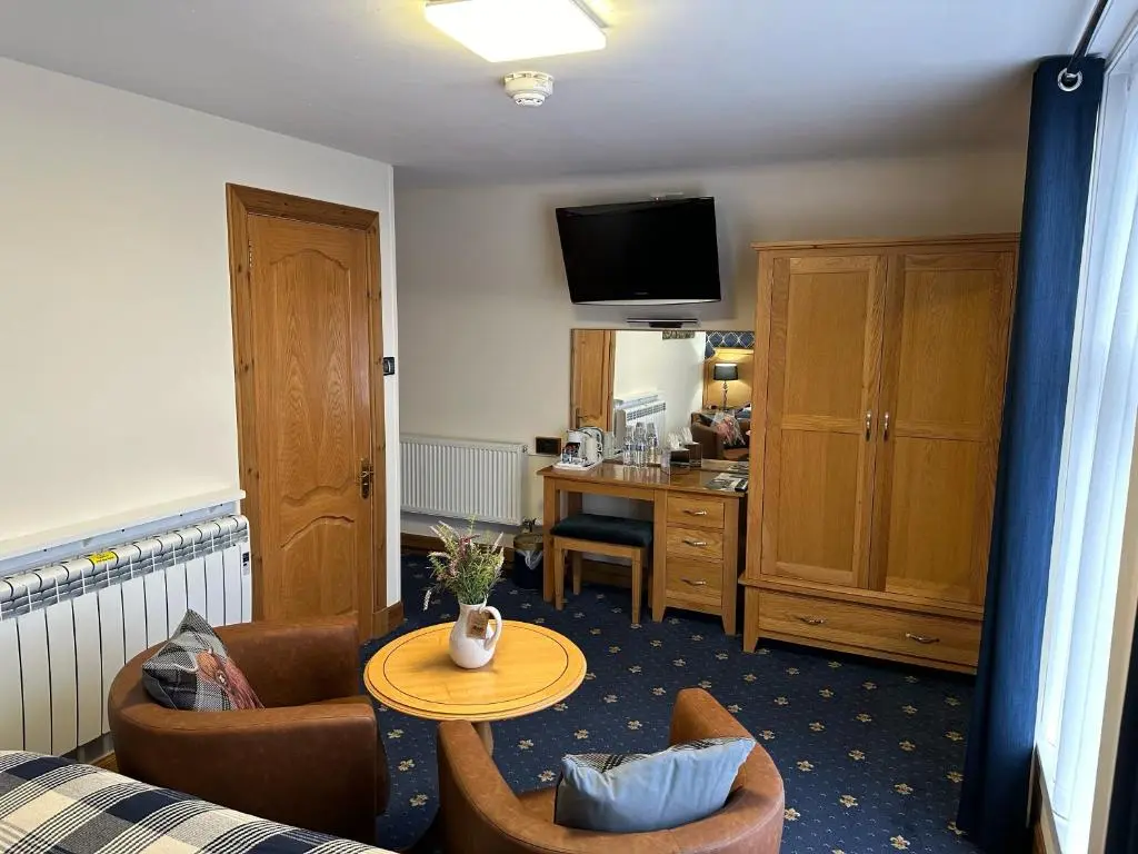 a living room with a couch and a table at The Glen Hotel Newtonmore - Rooms, bar & restaurant in Newtonmore