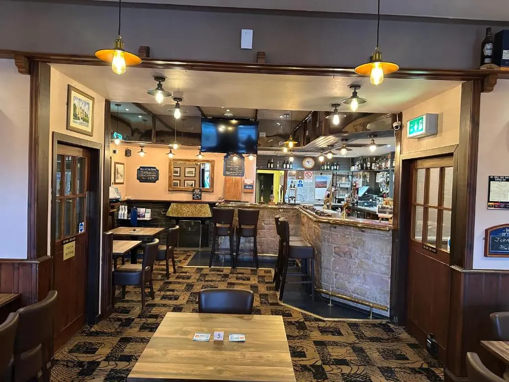 a restaurant with tables and chairs and a bar at The Glen Hotel Newtonmore - Rooms, bar & restaurant in Newtonmore