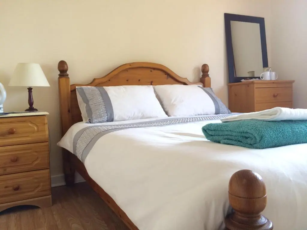 a bedroom with a large white bed with a wooden headboard at Invermac House in Inverness