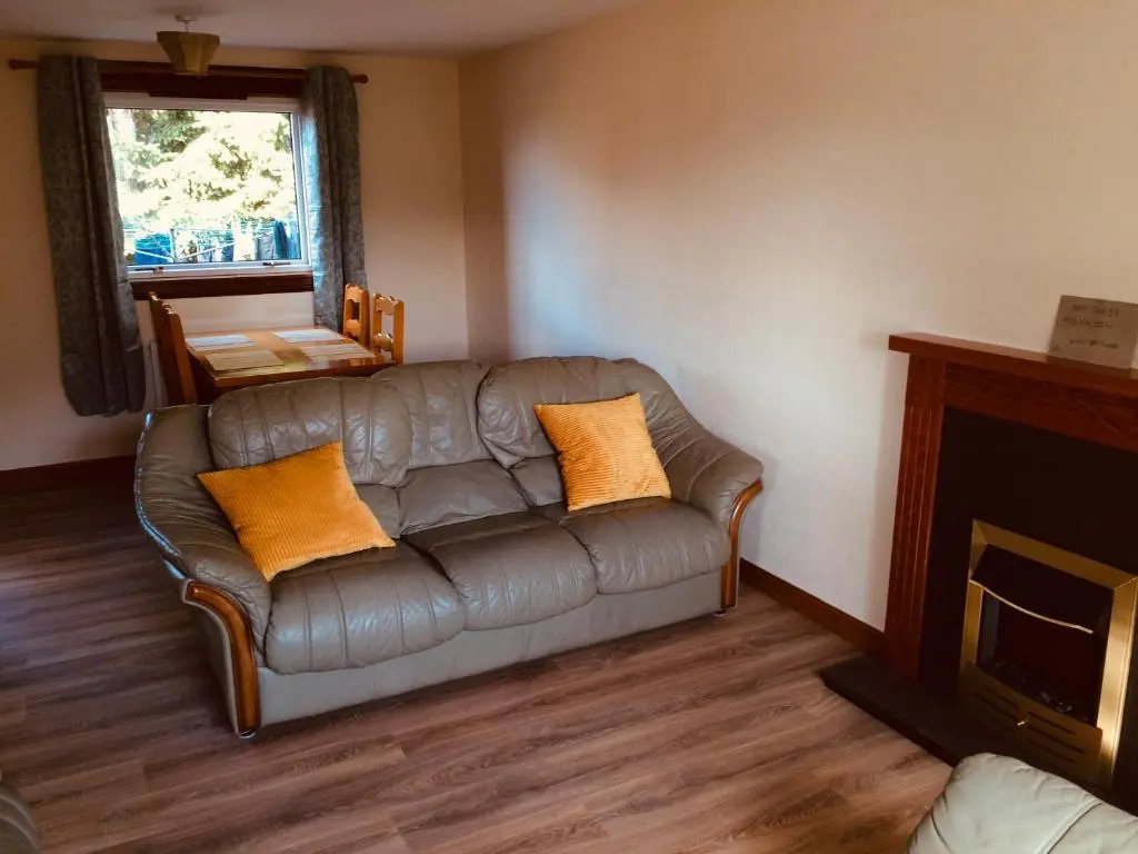 a living room with a leather couch with orange pillows at Invermac House in Inverness