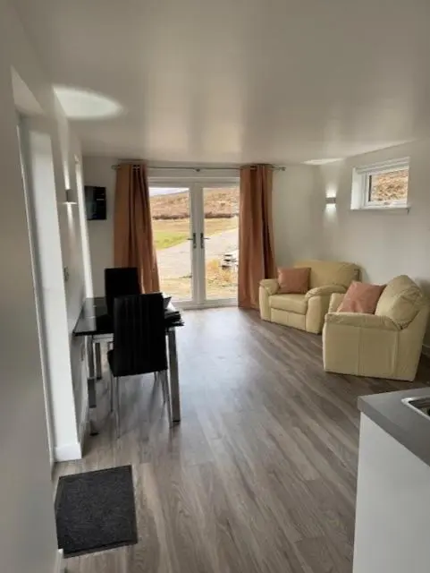 a living room with a couch and a table and chairs at Ledgowan Bunkhouse in Achnasheen