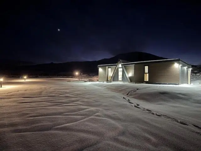 a building in the middle of a snow covered parking lot at night at Ledgowan Bunkhouse in Achnasheen