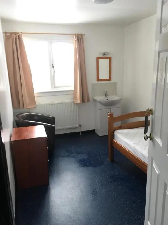 a bedroom with a bed and a sink and a window at Ledgowan Bunkhouse in Achnasheen