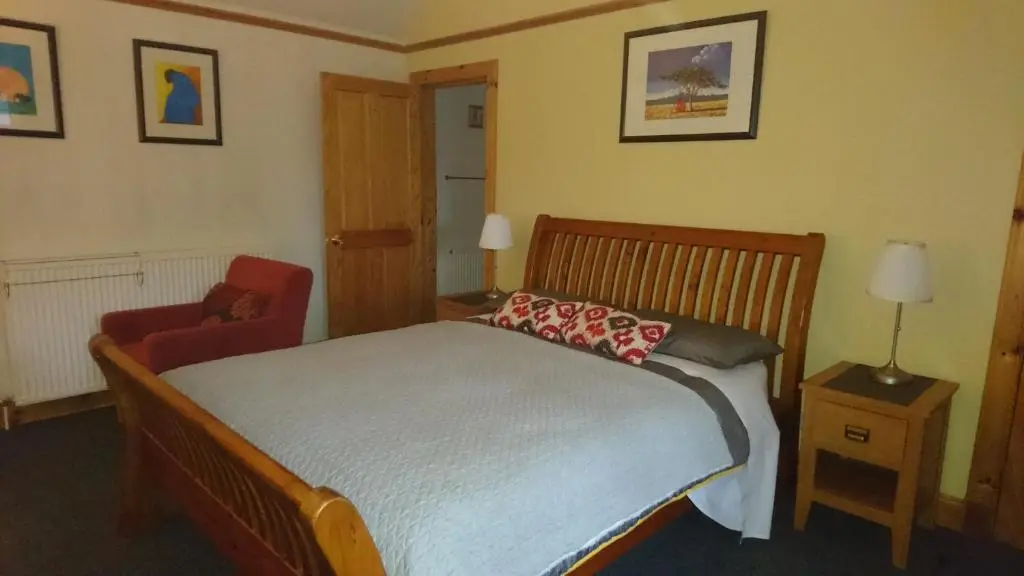 a bedroom with a bed and a red chair at Kindale House in Helmsdale