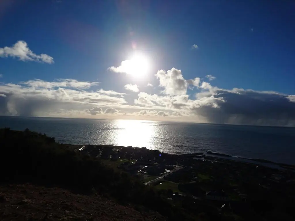 a bright sun in the sky over the ocean at Kindale House in Helmsdale