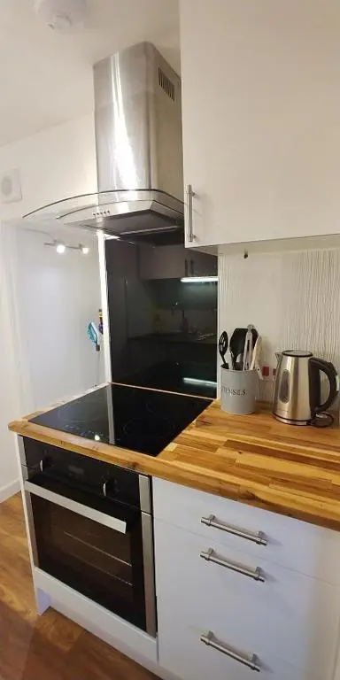 a kitchen with white cabinets and a stove top oven at Brae Cottage, Inverness in Inverness