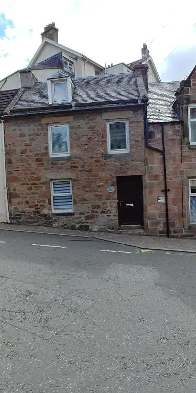 an old brick building with a door on a street at Brae Cottage, Inverness in Inverness