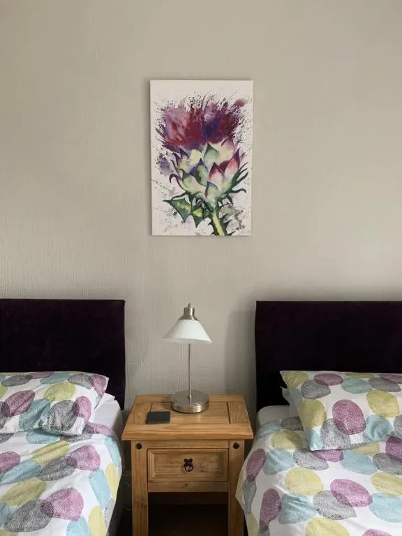 a bedroom with two beds and a table with a lamp at Eastdene Guest House in Inverness