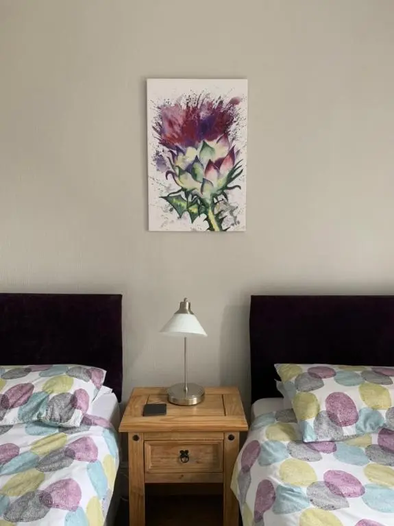 a bedroom with two beds and a table with a lamp at Eastdene Guest House in Inverness