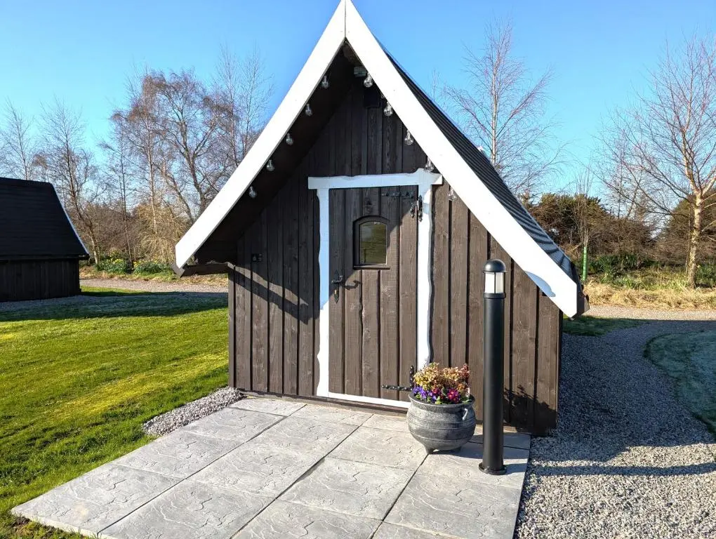 a small brown building with a flower pot in front at Macbeth's Hillock in Forres