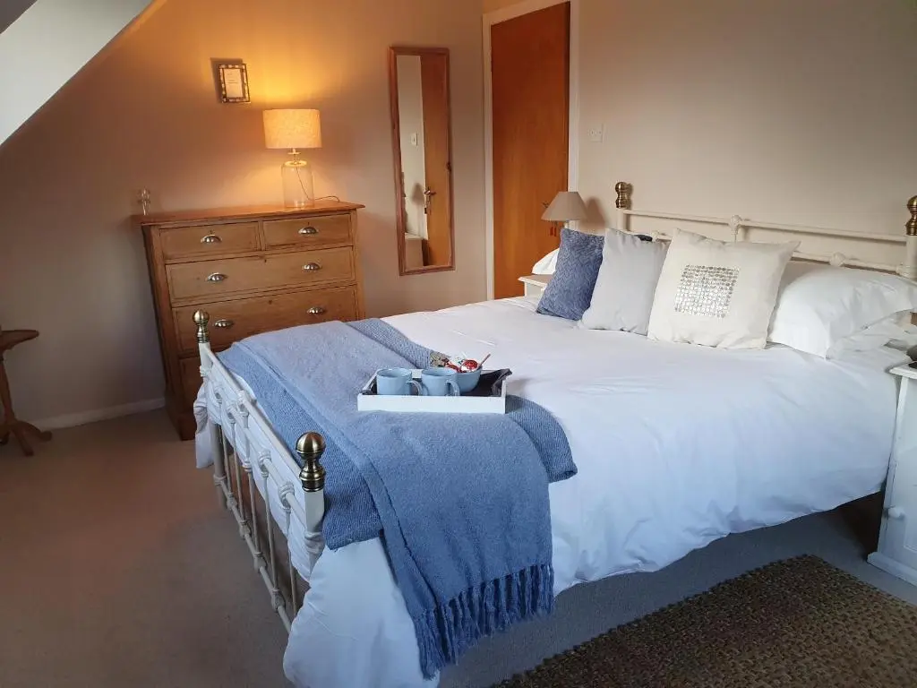 a bedroom with a large white bed with a blue blanket at Clachan Farmhouse B & B in Ullapool