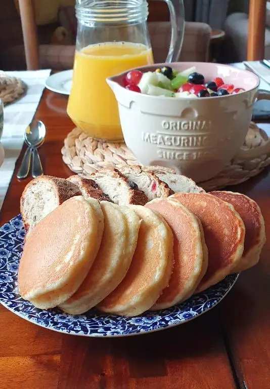 a table with a plate of bread and a bowl of fruit at Clachan Farmhouse B & B in Ullapool