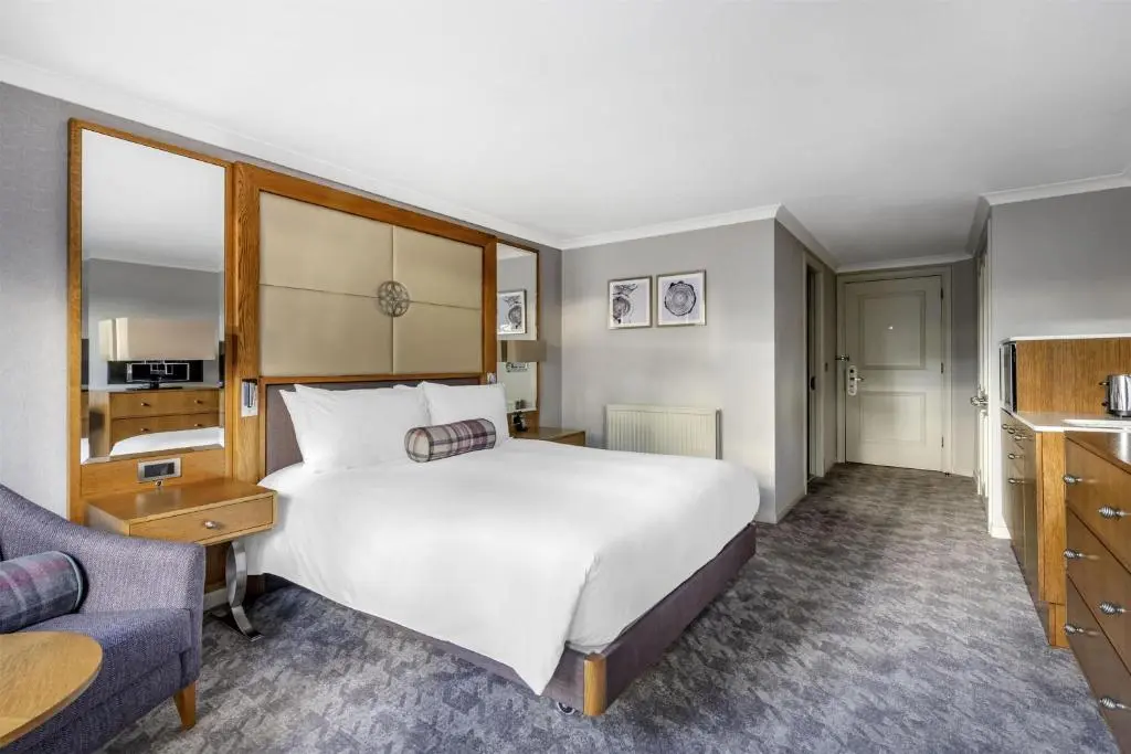 a hotel room with a large bed and a chair at Hilton Grand Vacations Club Craigendarroch Suites Scotland in Ballater