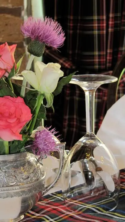 a glass wine glass sitting next to a vase of flowers at Loch Ness Lodge Hotel in Drumnadrochit