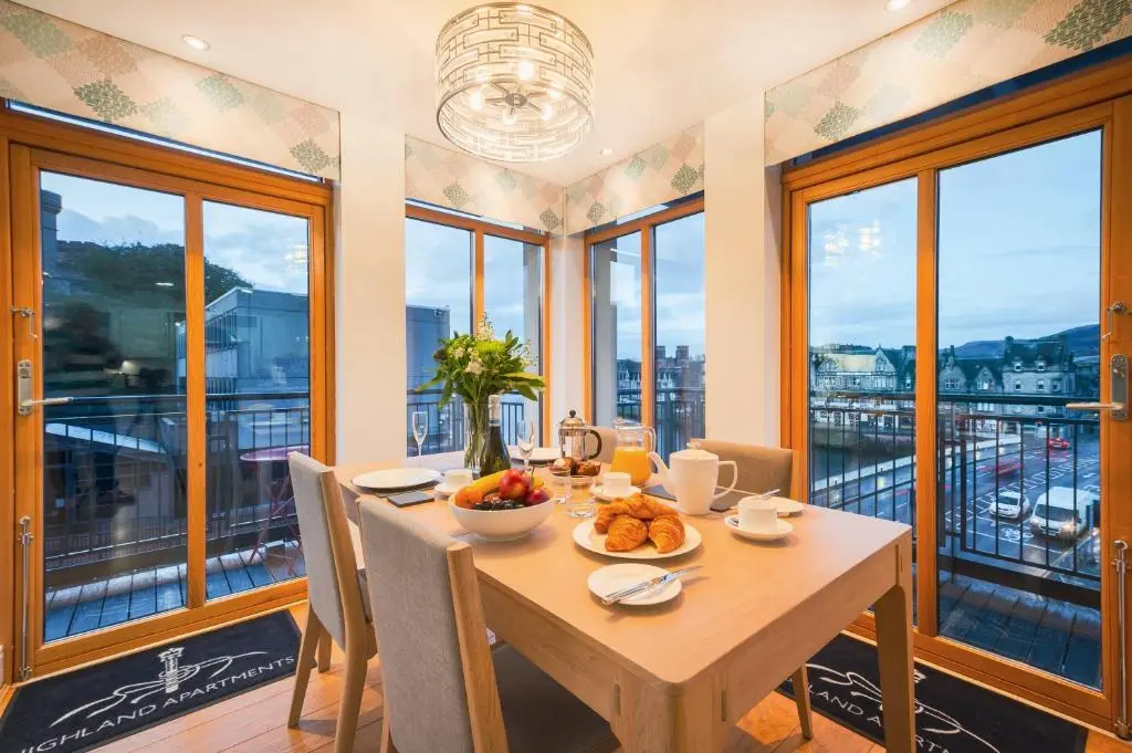 a dining room with a table and chairs and windows at Highland Apartments by Mansley in Inverness