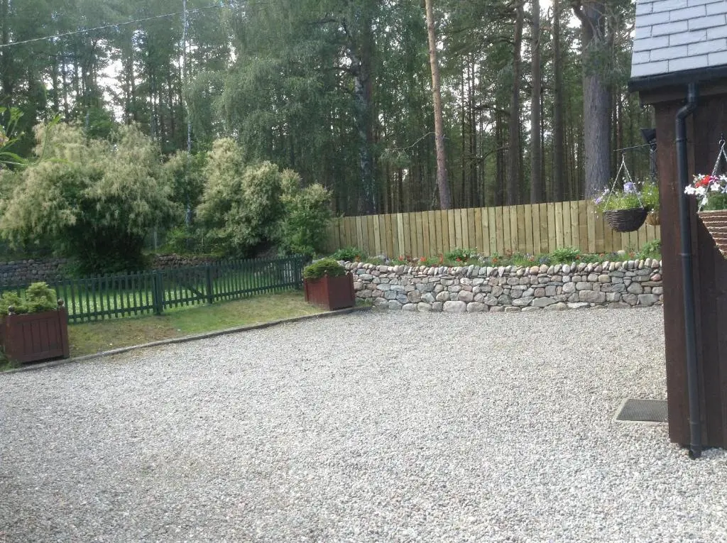 a backyard with a stone wall and a fence at Coylumbridge Cottage in Aviemore