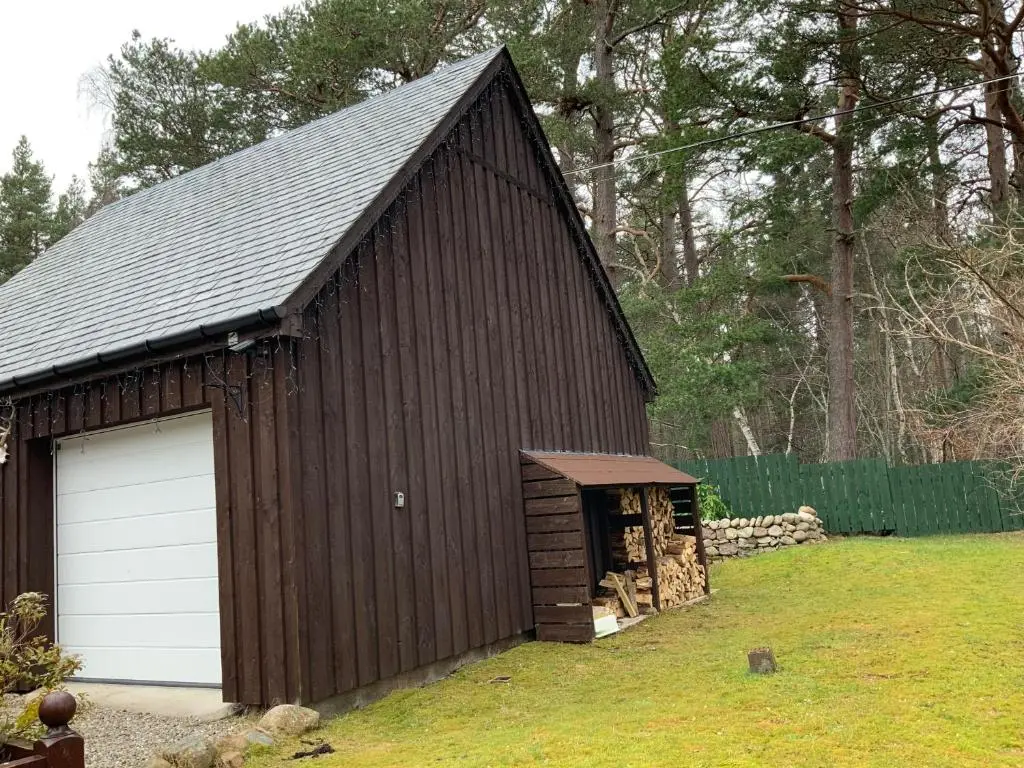 a large brown barn with a white garage at Coylumbridge Cottage in Aviemore