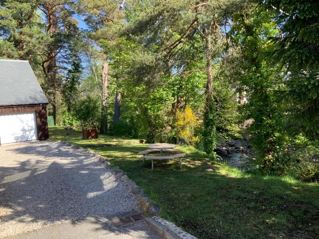 a picnic table in the grass next to a cabin at Coylumbridge Cottage in Aviemore