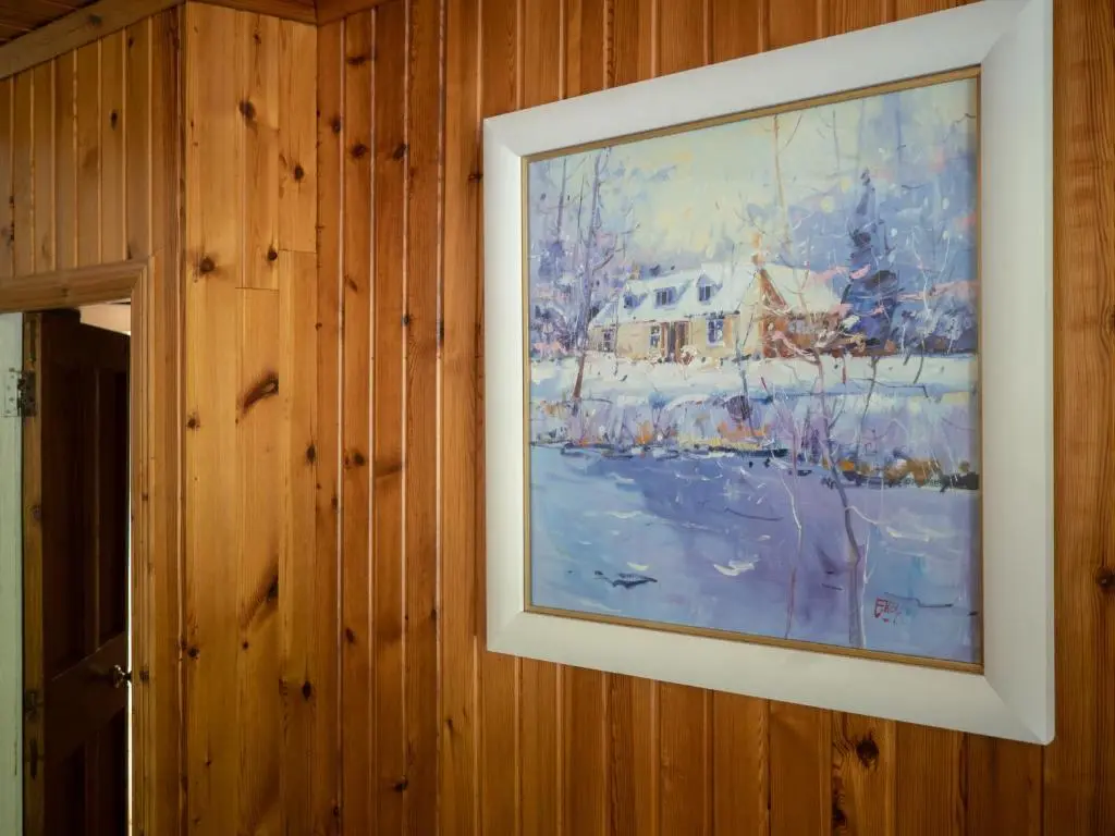 a painting of a house in the snow on a wall at Coylumbridge Cottage in Aviemore