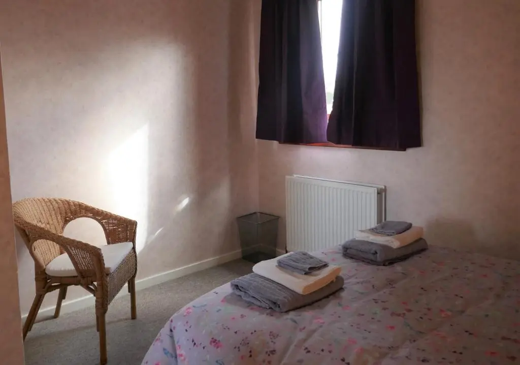 a bedroom with a bed with a chair and a window at Inverness Family House in Inverness