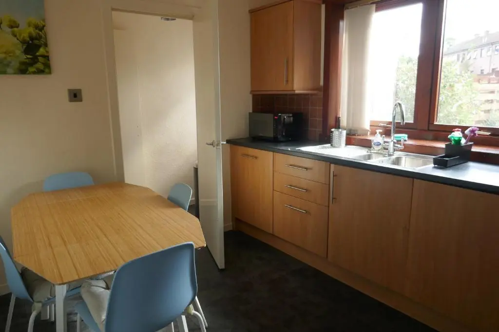 a kitchen with a wooden table and a table and chairs at Inverness Family House in Inverness