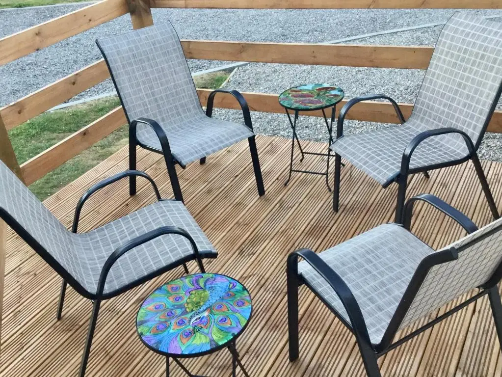 three chairs and a table on a deck at Poppy Lodge in Boat of Garten