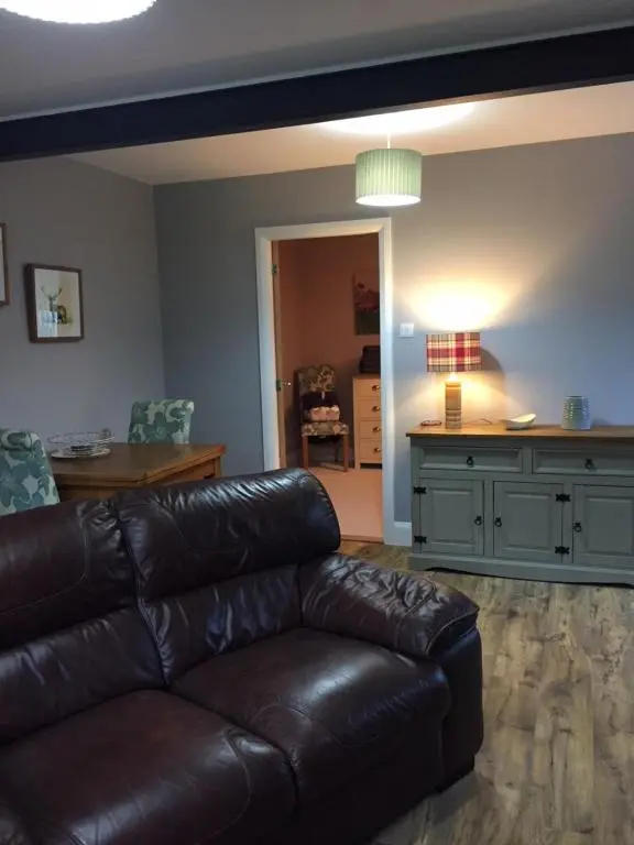 a living room with a leather couch and a table at Ridgewood Apartment in Drumnadrochit
