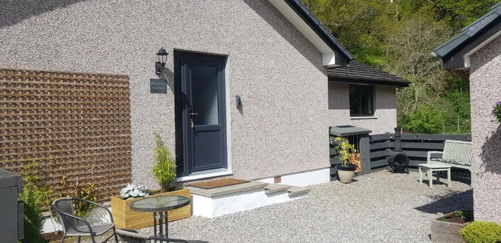 a house with a blue door and a table and chairs at Ridgewood Apartment in Drumnadrochit