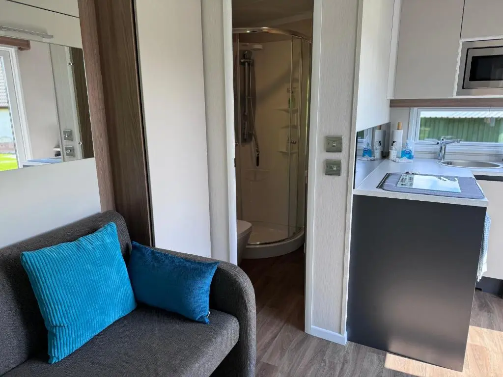 a room with a couch and a sink and a bathroom at The Garden Room Tiny House Bed and Breakfast Stay in Glenmoriston