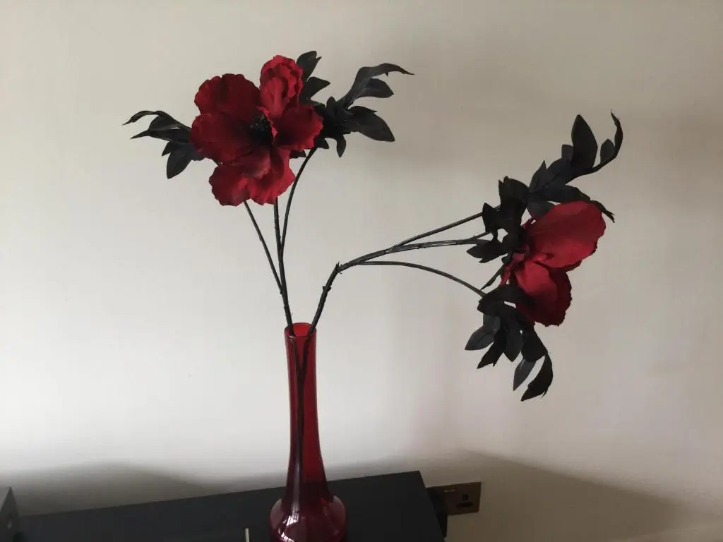 a red vase with two red flowers in it at Castlefield Apartment Free Parking in Inverness