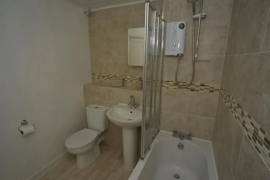 a bathroom with a toilet and a sink and a shower at Silver Key Apartments in Inverness