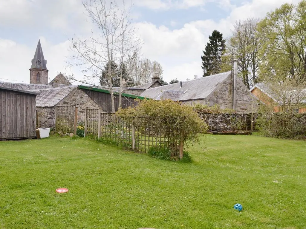 a yard with a fence and a church at Larch Cottage in Balnald