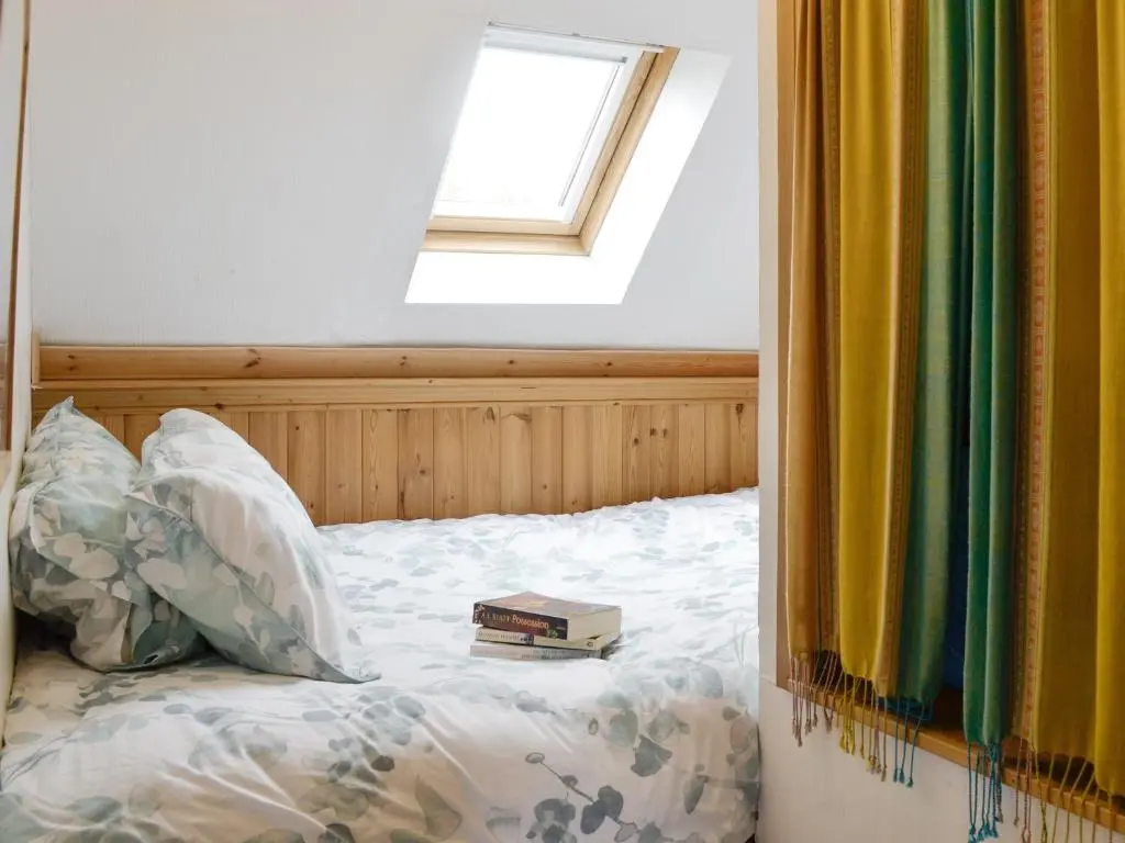 a bed with a book on it with a window at Larch Cottage in Balnald
