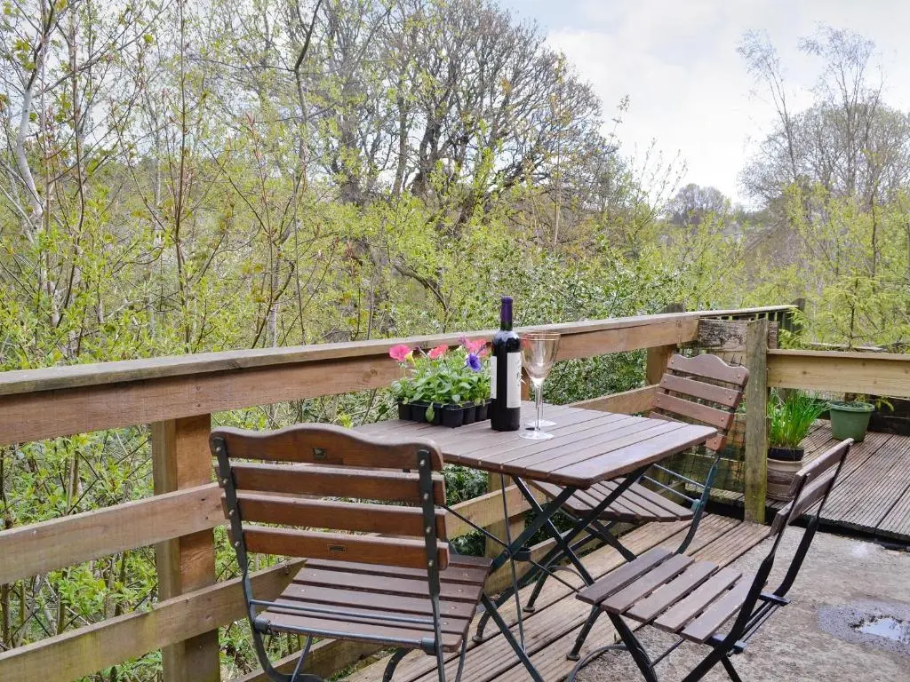 a wooden table with two chairs and flowers on a deck at Larch Cottage in Balnald