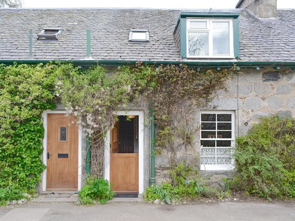 a brick house with a wooden door and a window at Larch Cottage in Balnald