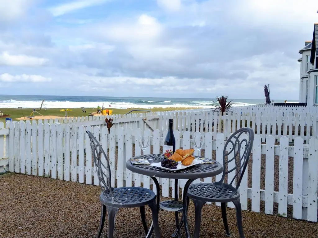 a table with a bottle of wine and two chairs at Seascape in Whitehills