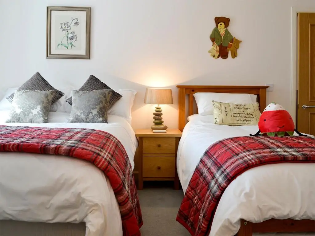 a bedroom with two beds and a red bird sitting on the bed at Seascape in Whitehills